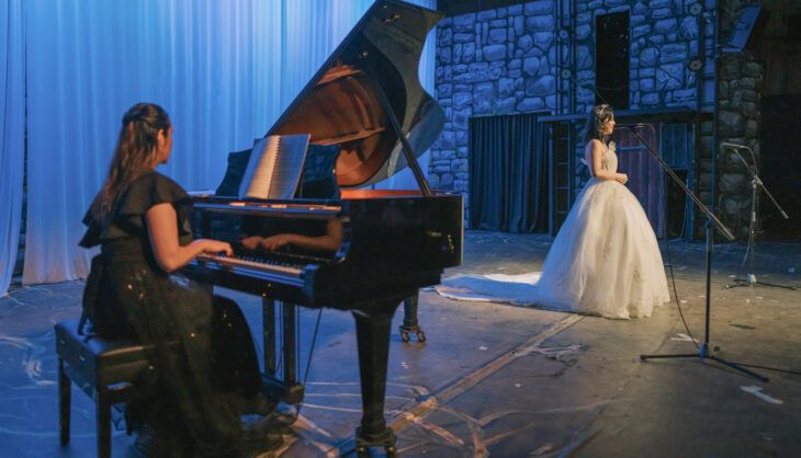 An opera singer on stage with a pianist