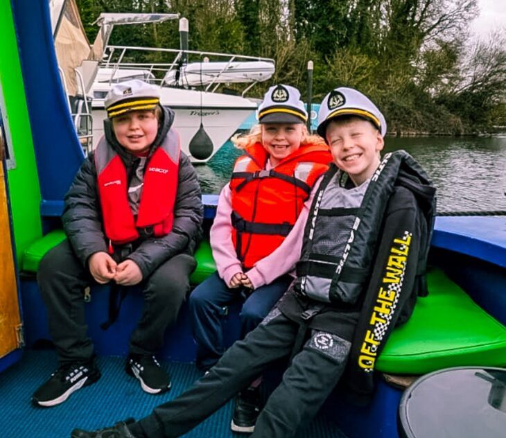 Three children sit aboard Momentum Children's Charity's riverboat on The Thames.