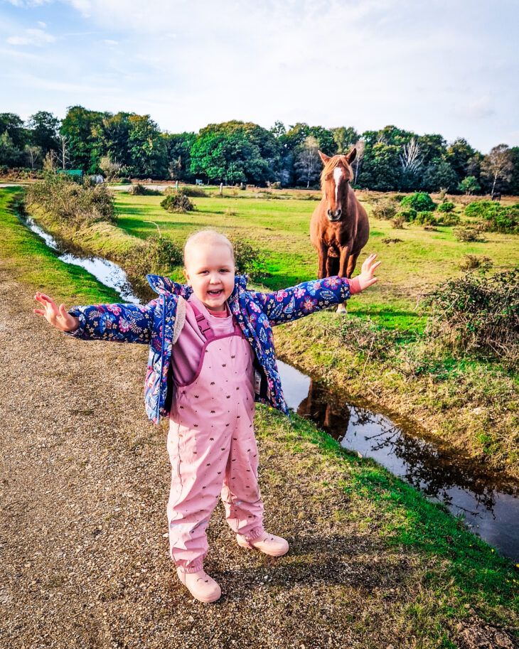 Isla standing beside a horse in the New Forest on a Momentum respite break