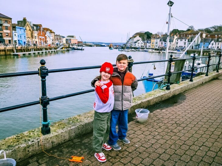 A young girl and boy who are siblings embrace each other on holiday.