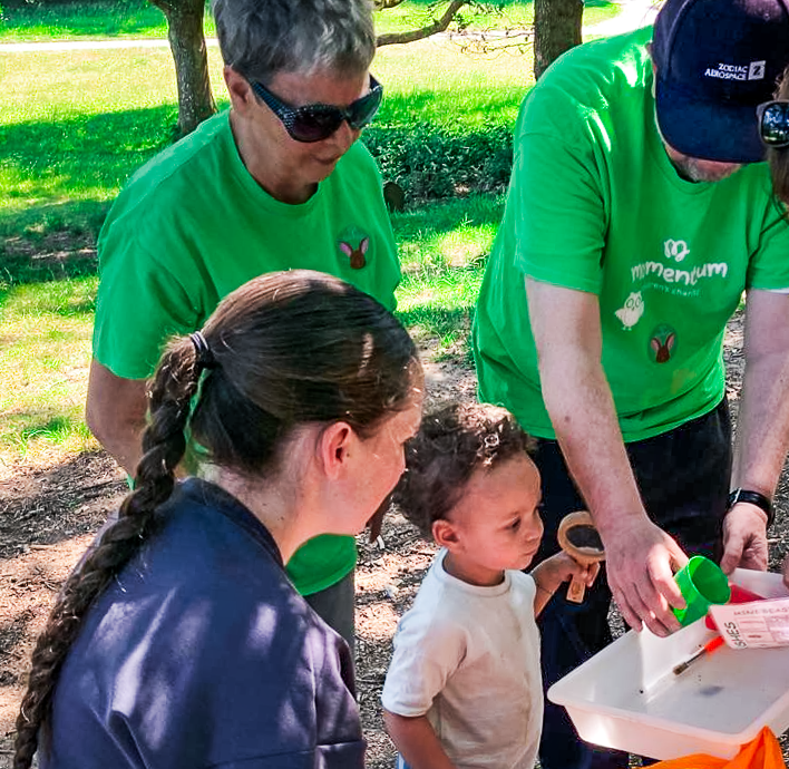 A young boy and his mum gather with two volunteers from Momentum Children's Charity for den building event.