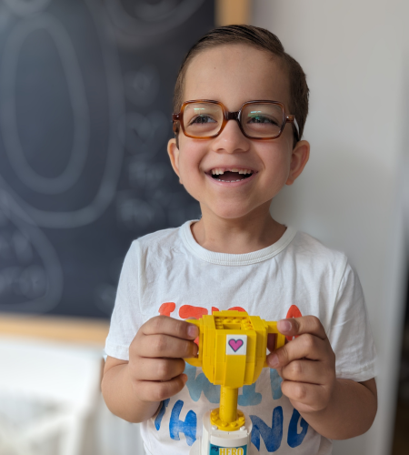Child supported by Momentum Children's Charity smiling while holding a handmade Lego trophy